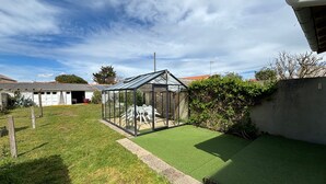 A house with a glass greenhouse, a lawn, and a shed. - Charming 2-Bedroom House with Garden Near Beach and Port Olona (Les Sables-d'Olonne)