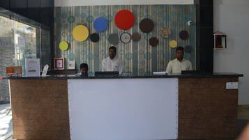 A reception desk with a patterned wall behind it, a clock, and a small shelf with a decorative item.