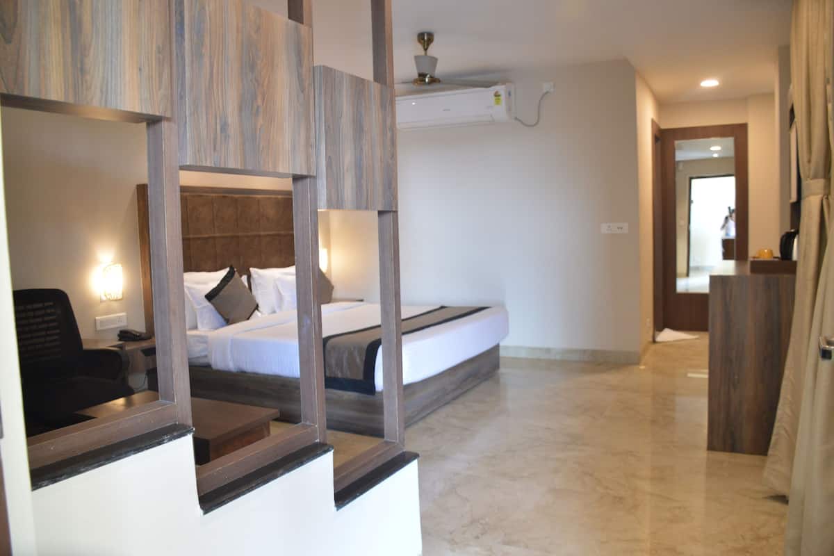 Quarto de hotel com cama, mesa de cabeceira, abajur e espelho.