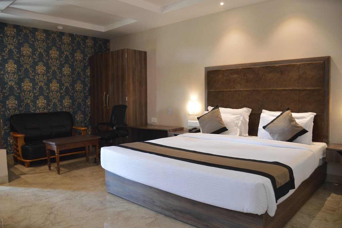 Quarto de hotel com uma cama grande, cabeceira de madeira, escrivaninha, cadeira e guarda-roupa.