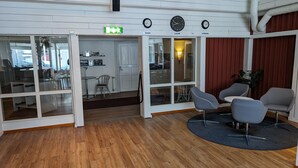 A modern interior with a wooden floor, glass doors leading to a dining area, and a seating area with chairs and a table. - Örnvik Hotell & Konferens (Luleå)