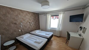 A hotel room with two beds, a desk, a TV, and a small table. - Örnvik Hotell & Konferens (Luleå)