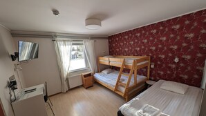 A bedroom with a bunk bed, a desk with a chair, a radiator, a window with curtains, and a mirror on the wall. - Örnvik Hotell & Konferens (Luleå)