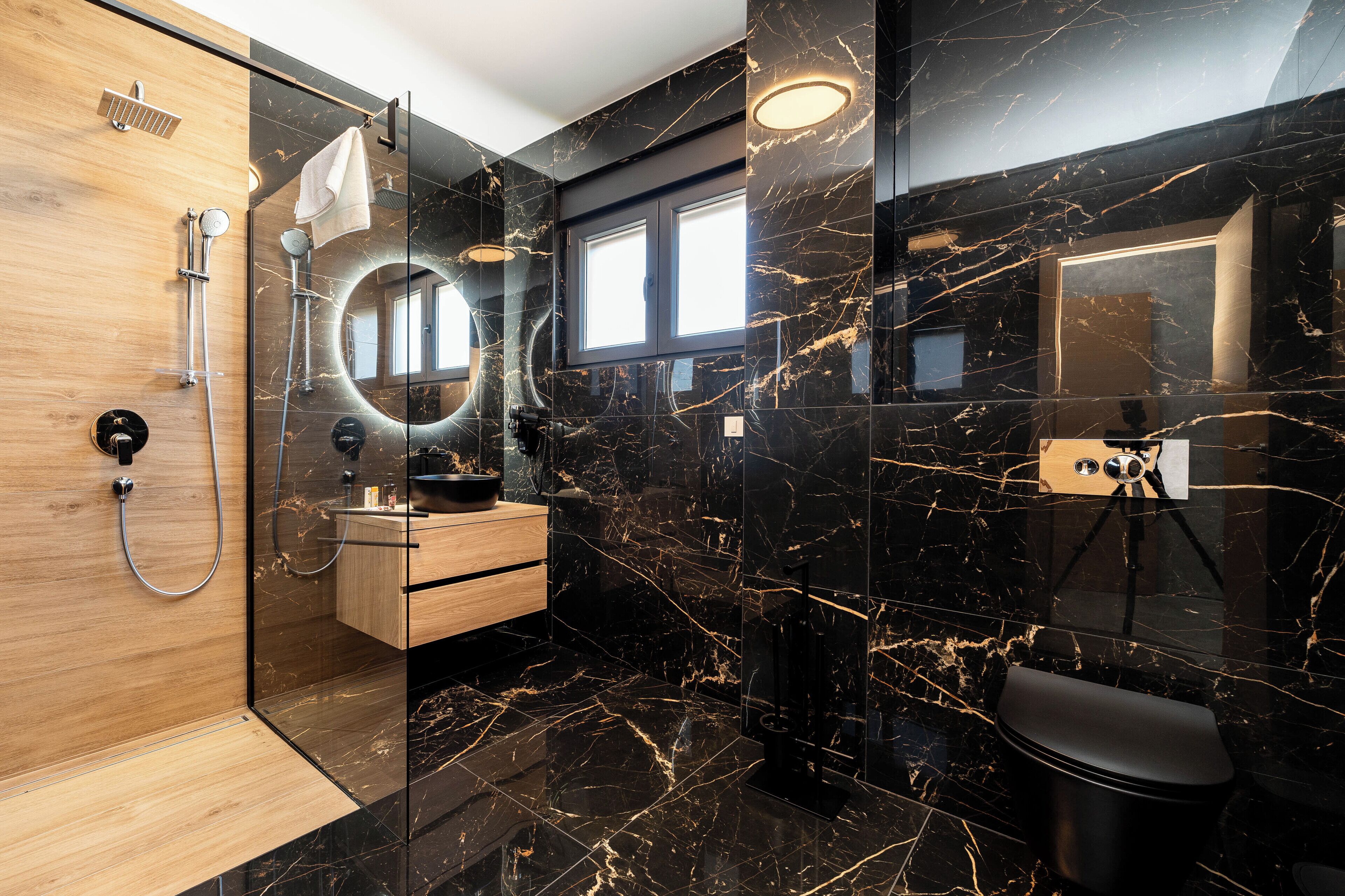 Un bagno moderno con box doccia in legno, un mobile lavabo con specchio e un water.
