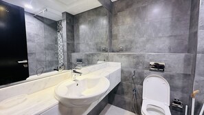 Un baño moderno con un espejo grande, un lavabo blanco, una bañera y un inodoro.