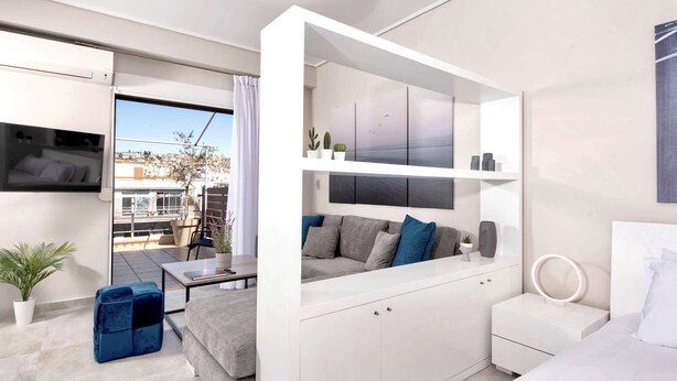 A modern, compact living space with a balcony, a sofa, a small table, and a white cabinet. - Pearl: Penthouse suite with city view (Thessaloniki)
