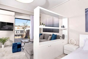 Un espace de vie moderne et compact, doté d’un balcon, d’un canapé, d’une petite table et d’un meuble blanc.