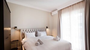 Une chambre d’hôtel avec un grand lit, une petite table ronde et un système de climatisation intégré.