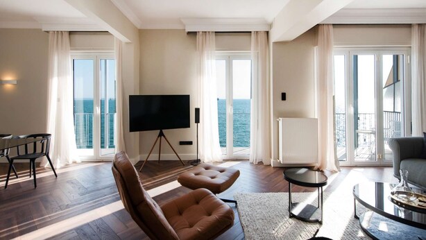 Un salon spacieux doté d’un grand téléviseur à écran plat, de sièges confortables et offrant une vue sur la mer grâce à de grandes fenêtres.