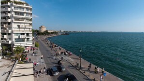 Une promenade en bord de mer agrémentée d’une tour historique, d’un bâtiment moderne et offrant une vue dégagée sur la mer.