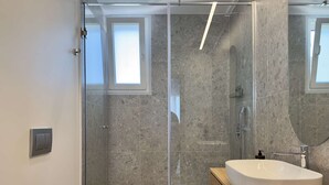 Un baño moderno con ducha envuelta en vidrio, una bañera independiente grande y un tocador de madera.