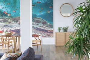 Een kamer met een grote wandaquarium, een eetgedeelte met houten meubels en een potplant.