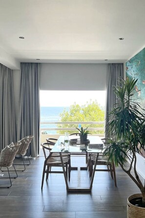 A modern dining area with a view of the sea, a large table, and chairs. - Modern Clifton Apartment - Number 5101 (Cape Town)