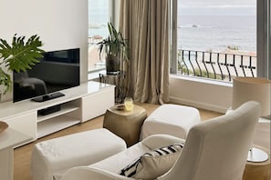 A modern living room with a television, seating, a potted plant, and a view of the sea. - Unique Studio Apartment - Number 4704 (Cape Town)