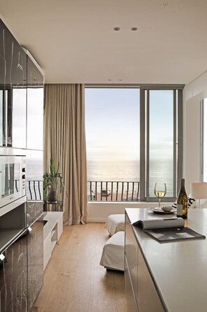 A modern kitchen with a large window, a dining area, and a view of the sea. - Unique Studio Apartment - Number 4704 (Cape Town)