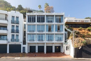 A multi-story building with balconies, a garage entrance, and a hillside backdrop. - Unique Studio Apartment - Number 4704 (Cape Town)