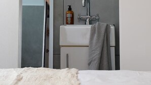 Une salle de bain moderne avec un lavabo blanc, un miroir et une douche.