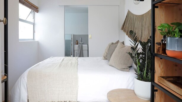 Une chambre à coucher avec un lit, une table de chevet et une plante en pot.