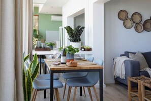 A dining area with a wooden table, blue chairs, and potted plants.