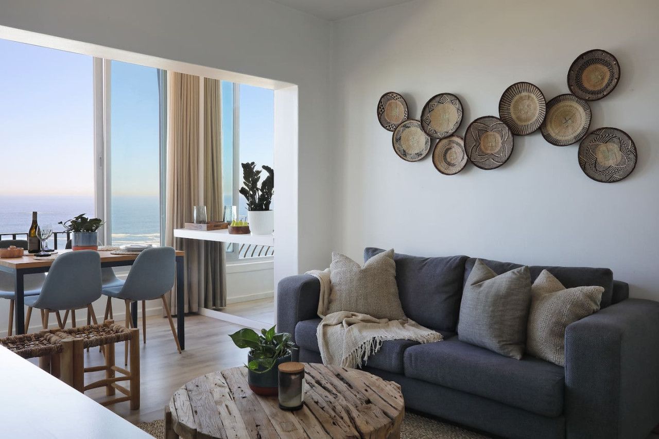 Una sala de estar moderna con un sofá gris, una mesa de centro y un comedor con sillas y una mesa.