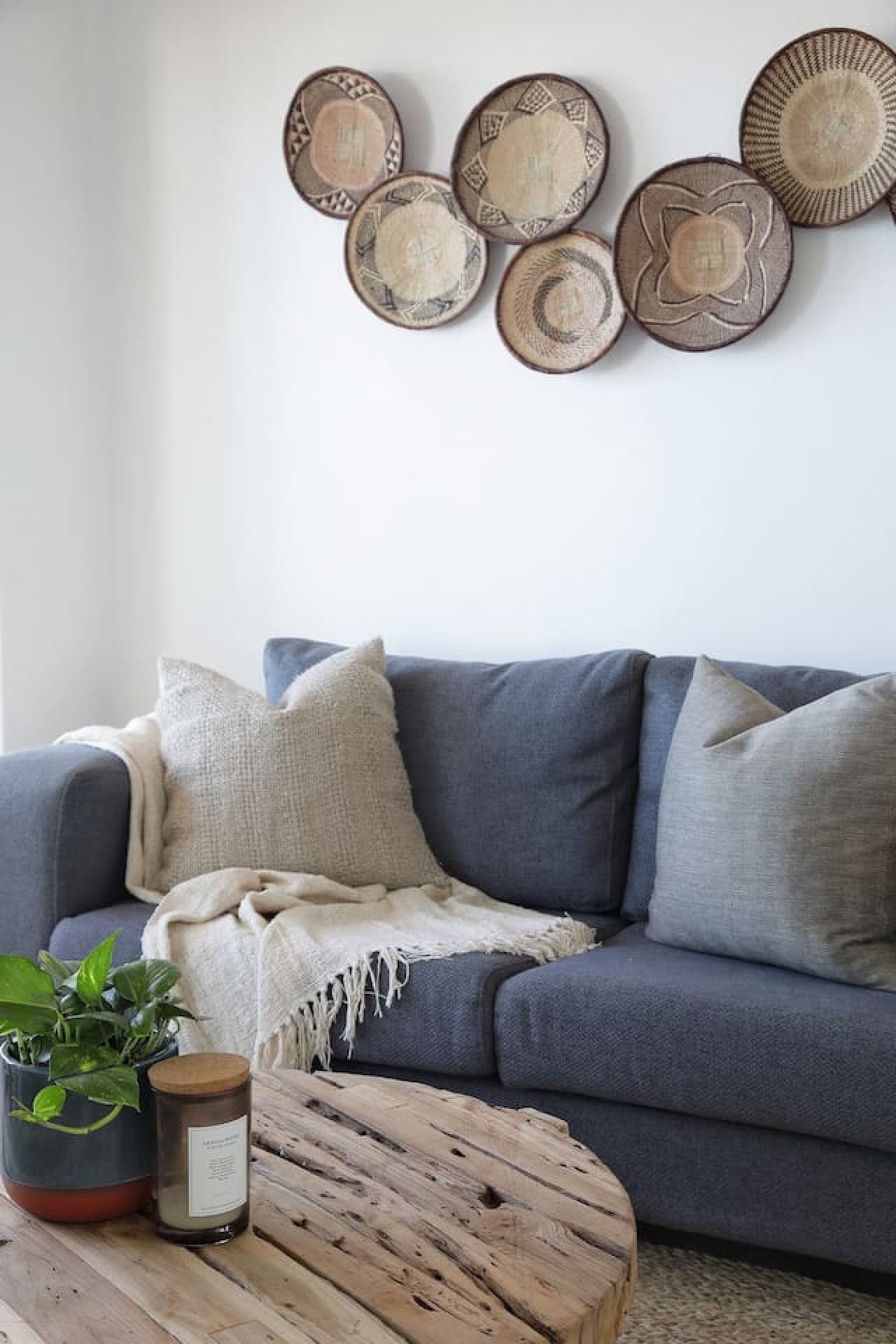 A living room with a grey sofa, a wooden coffee table, and a wall decorated with circular wall art.