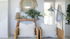 A room with two wicker chairs, a round mirror, a lamp, and a potted plant. - Comfortable 3 Bedroom Apartment - Number 5103 (Cape Town)