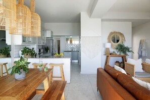 A modern kitchen with white cabinets, a wooden island, and hanging wicker light fixtures.