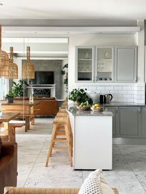 A modern kitchen with white cabinets, a central island, and a dining area with wooden furniture.
