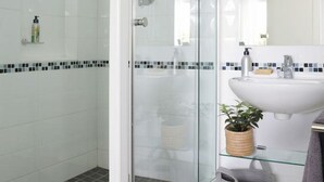 A modern bathroom with a glass-enclosed shower, a white sink, and a mirror. - Comfortable 3 Bedroom Apartment - Number 5103 (Cape Town)