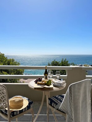 Ein Balkon mit Tisch für zwei Personen, mit Blick auf das klare, blaue Meer.