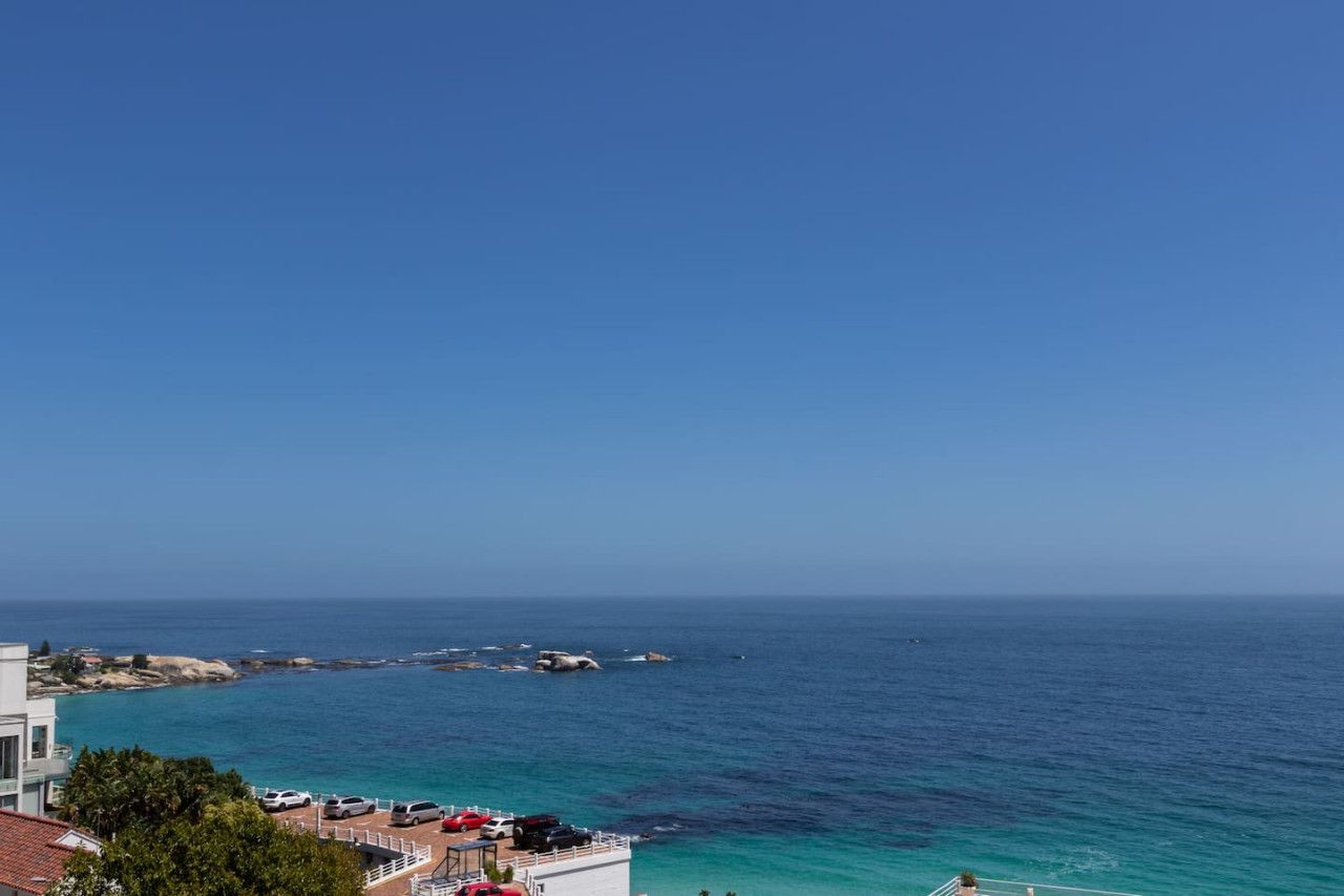 Ein Küstenblick mit blauem Himmel, ruhiger See und Häusern mit Balkonen mit Blick auf das Wasser.