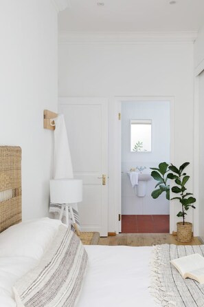 A bedroom with a bed, bedside lamp, and a potted plant.