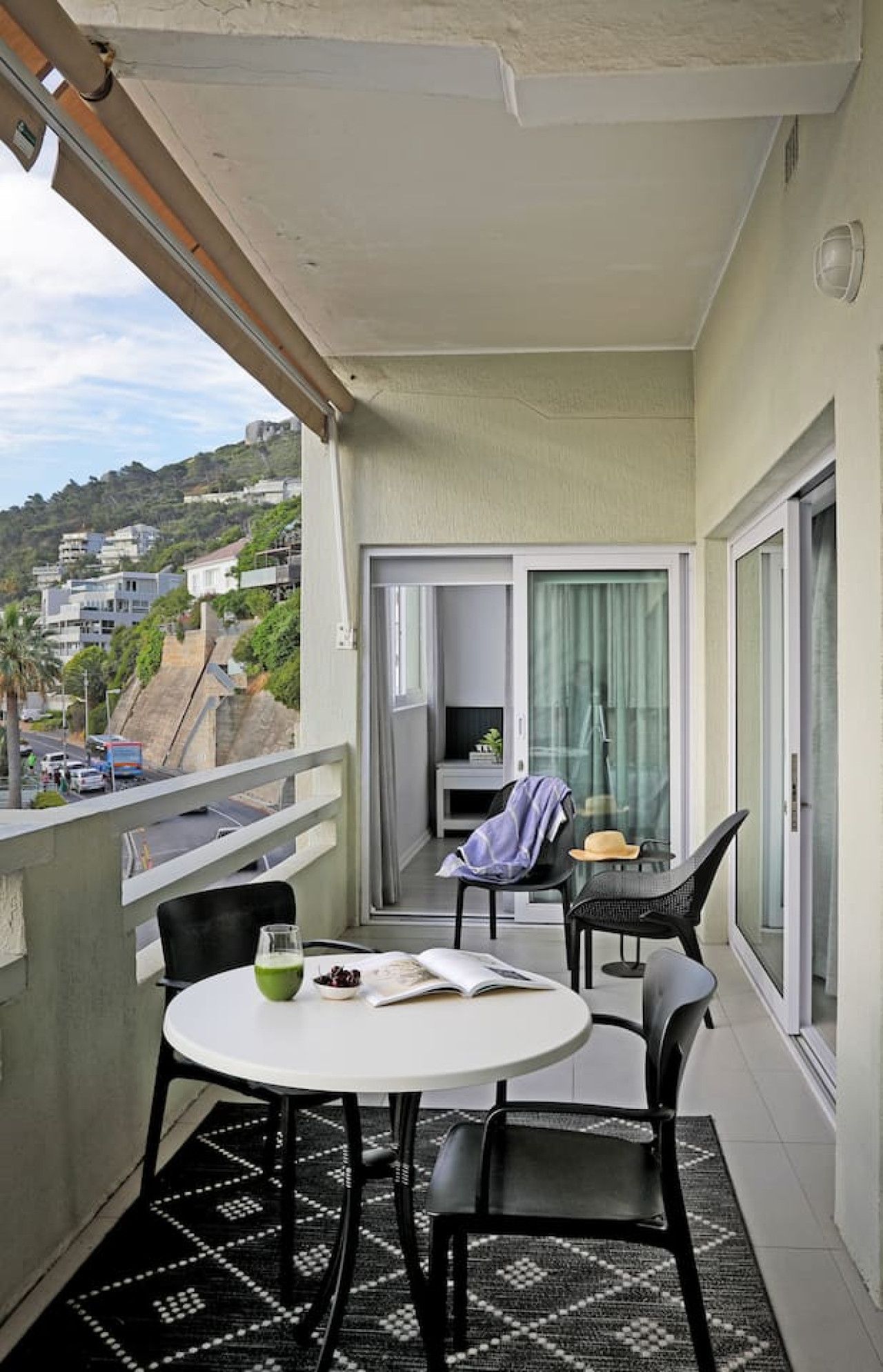Ein Balkon mit Tisch und Stühlen, einem Fernseher und Blick auf die Stadt.