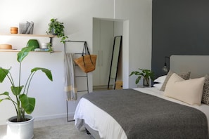 A modern bedroom with a bed, bedside tables, a hanging chair, and a large mirror. - Contemporary Clifton Apartment - Number 5104 (Cape Town)