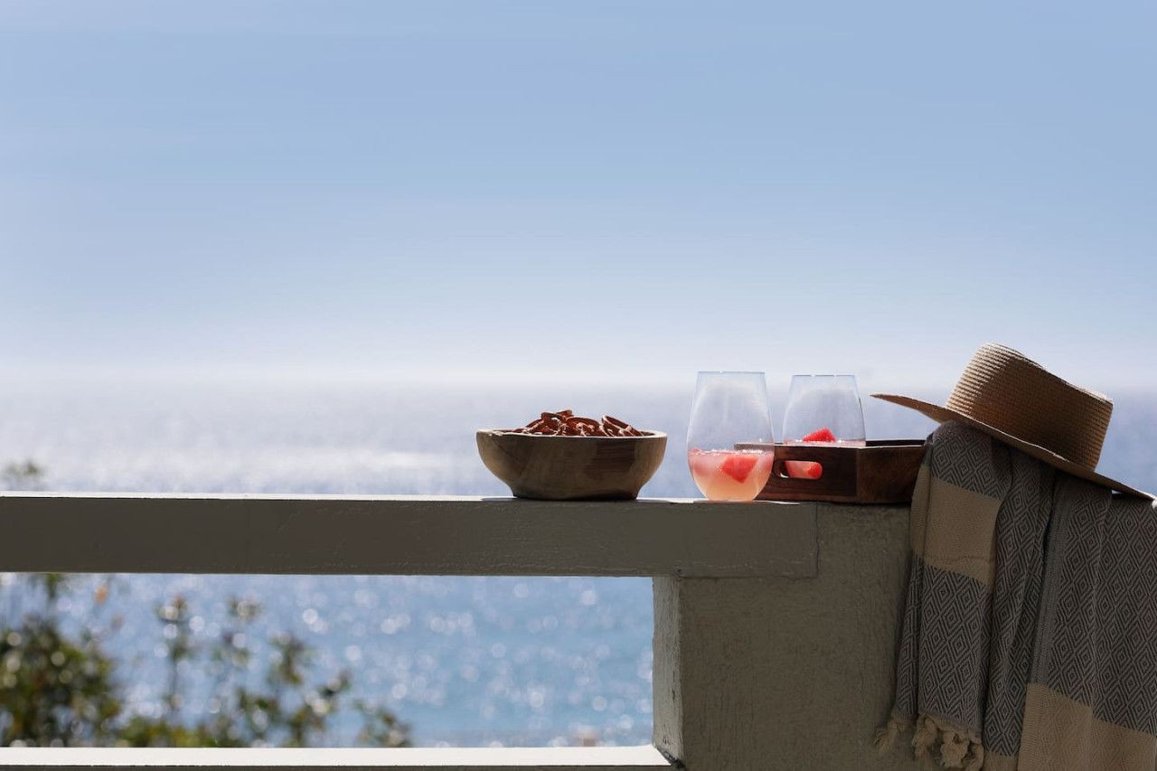 A balcony with a bowl of food, two glasses, and a hat.