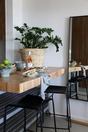 A modern kitchen with a wooden countertop, a potted plant, a bottle of olive oil, a bowl of fruit, and a stone mortar. - Contemporary Clifton Apartment - Number 5104 (Cape Town)