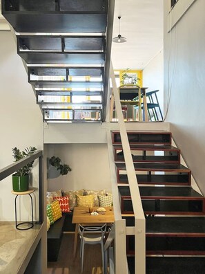 A modern interior with a staircase, a dining area, and a bookshelf.