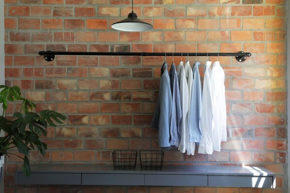 A brick wall with a clothes rack holding several garments.