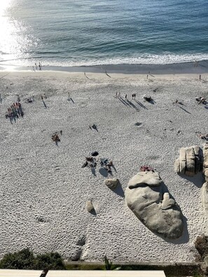 A beach with people scattered across the sand, large rocks, and the ocean in the background. - Stylish Clifton Apartment - Number 5102 (Cape Town)