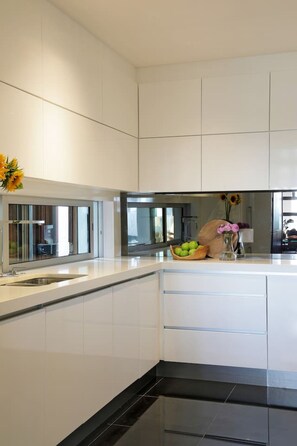 Una cocina moderna con armarios blancos, encimera negra y horno empotrado.