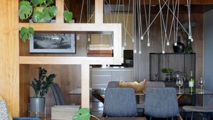 Una sala de estar moderna con un sofá azul, un comedor con sillas y una cocina al fondo.