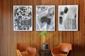 A room with wooden paneling, two brown chairs, and three abstract black-and-white paintings on the wall. - Stylish Clifton Apartment - Number 5102 (Cape Town)
