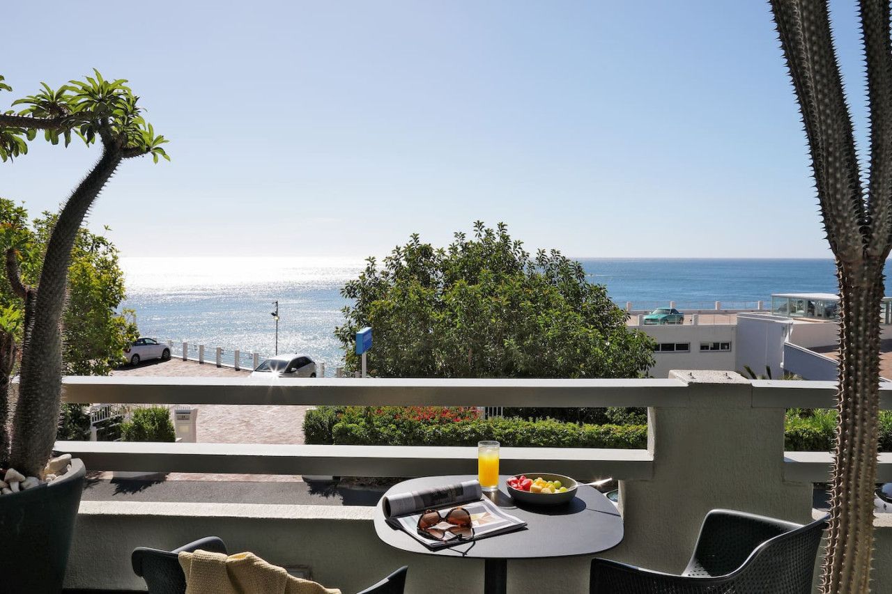 A balcony with a table set for breakfast, overlooking a coastal view.