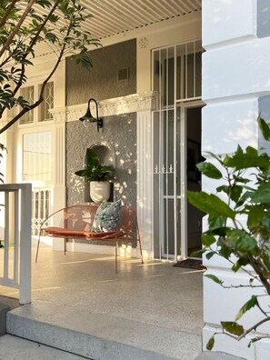 Área de estar coberta ao ar livre com banco e planta em vaso.