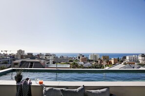 A rooftop pool with a view of the city and the ocean.