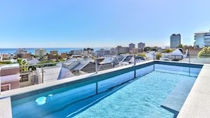 Une piscine sur le toit, offrant une vue sur la ville et entourée d’immeubles.