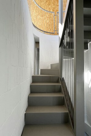 Escadaria com design moderno, paredes brancas e teto de madeira.