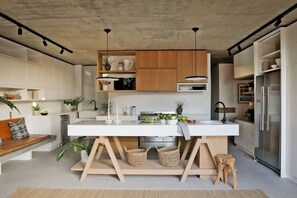 A modern kitchen with a central island, wooden cabinets, and pendant lighting.