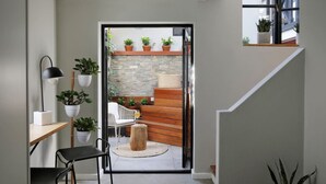 Een modern interieur met een trap naar een balkon, een eethoek met een tafel en stoelen, en potplanten.