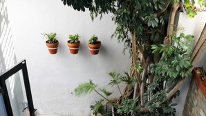 Een zwembadgedeelte met een houten terras, een witte buitenbank, een rieten stoel en een kleine ronde tafel met een schaal lekkernijen.